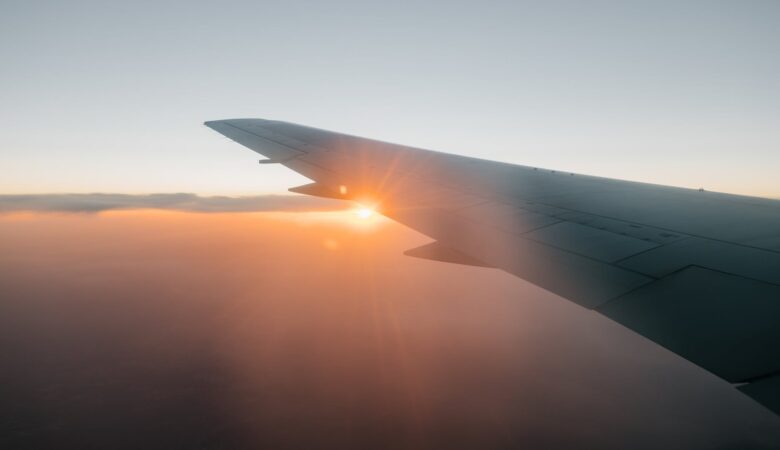wing of airplane flying against sunset