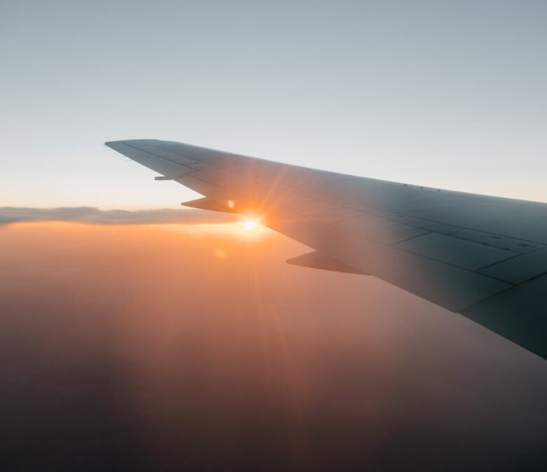 wing of airplane flying against sunset